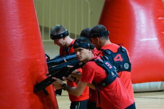 Игроки LASERWAR в красных жилетах держат оружие